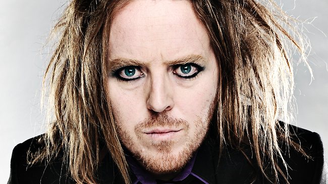 a long haired man with green eyes in a black suit
