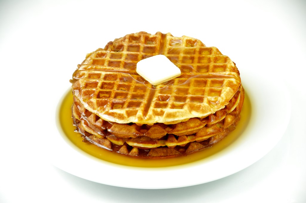a white plate with three waffles and syrup