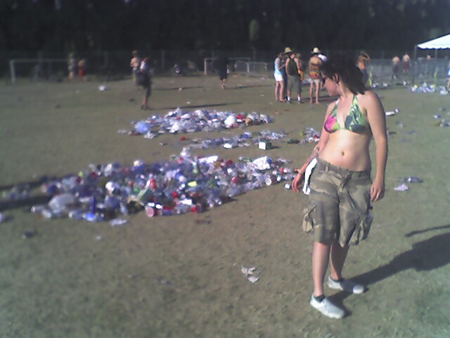 a woman in a bikini stands amongst piles of broken shirts