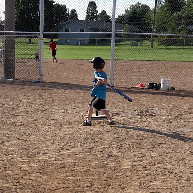 a boy on a baseball field holding a baseball bat