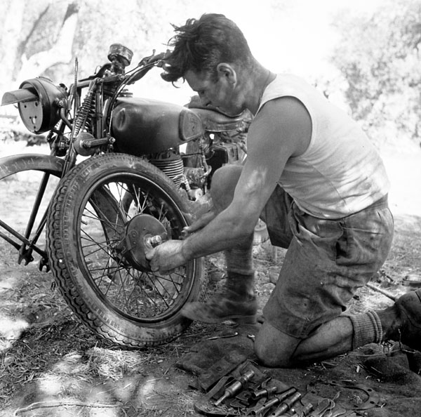 a man working on a bike next to a pile of tools