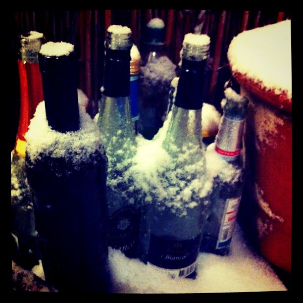 several bottles covered with snow near an ice bucket