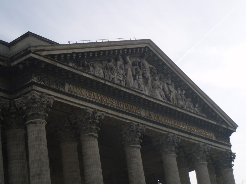 a building with statues on the roof and pillars