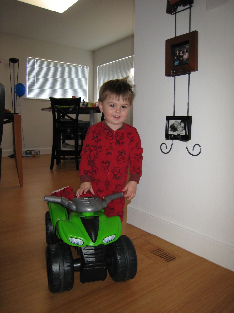 a small boy rides a toy tractor near the wall