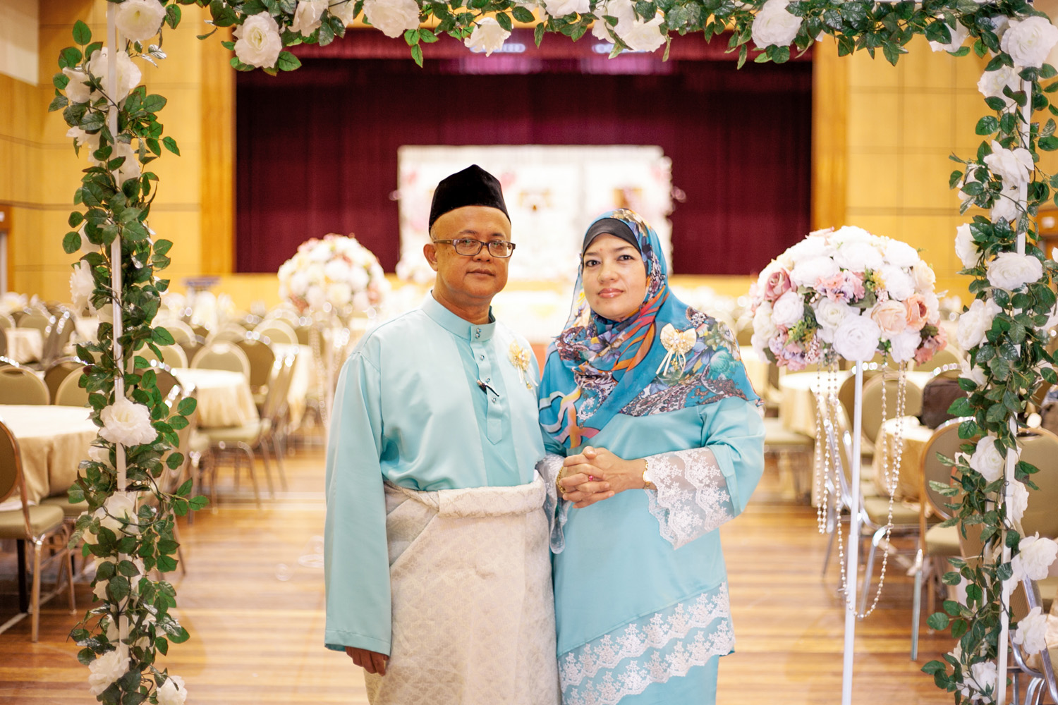 a man and woman are standing under an archway decorated with flowers