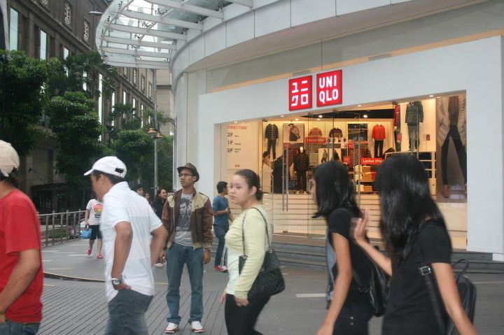group of people walking in a mall next to buildings