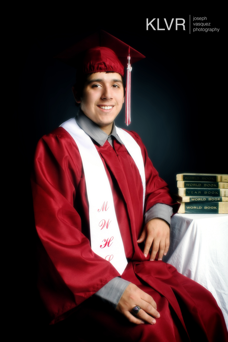 a man wearing a graduation cap and gown is posing with books