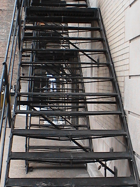 black and silver stairs leading up to the side of a building