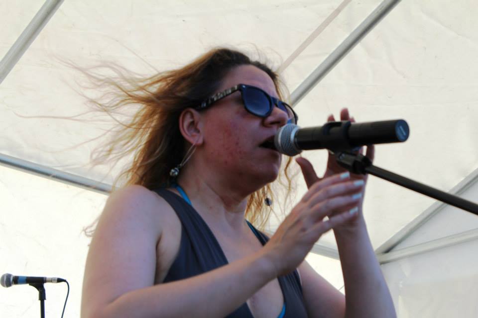 a woman in sunglasses on stage holding a microphone