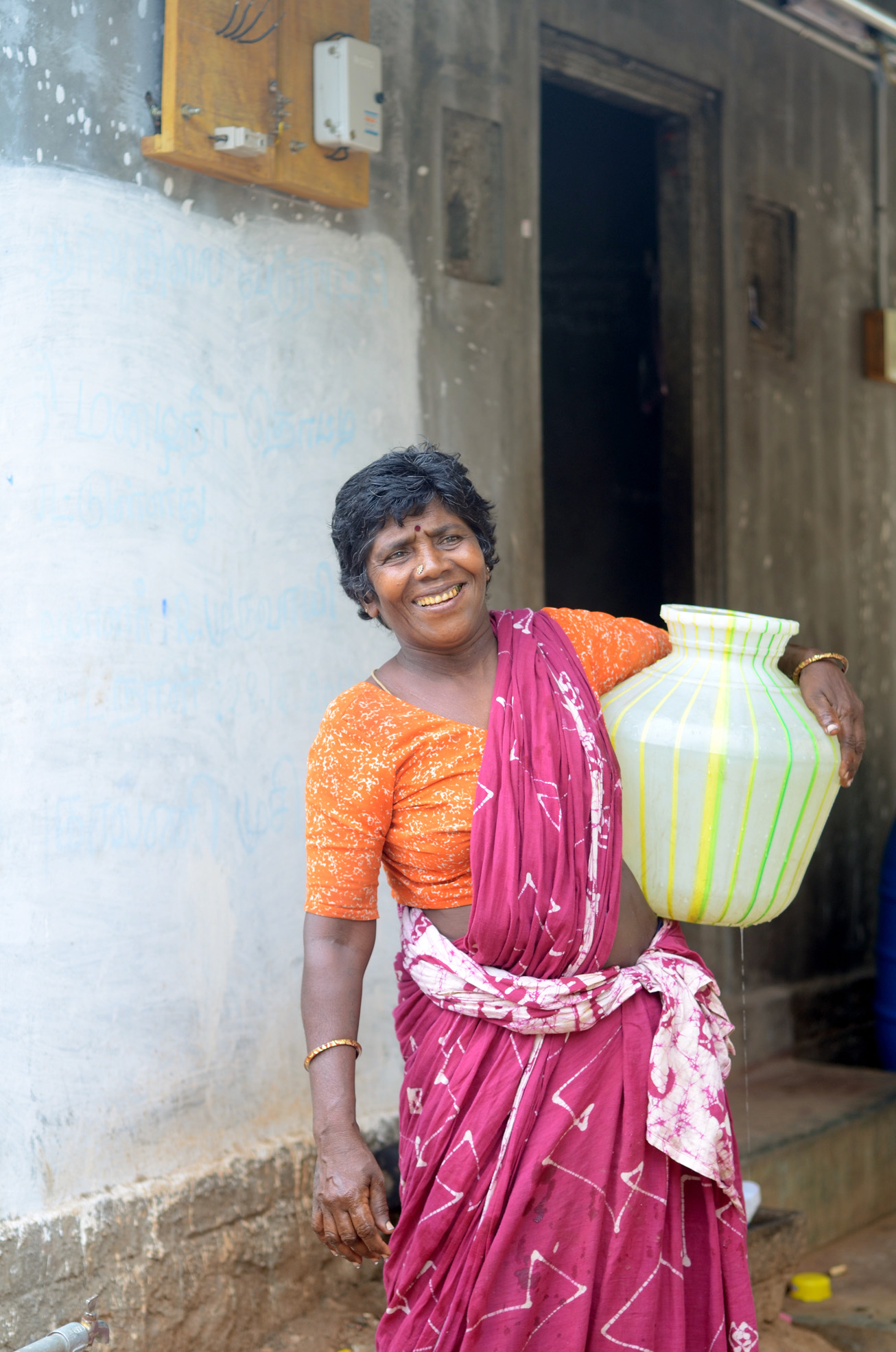 woman in orange and pink outfit carrying vase in hand