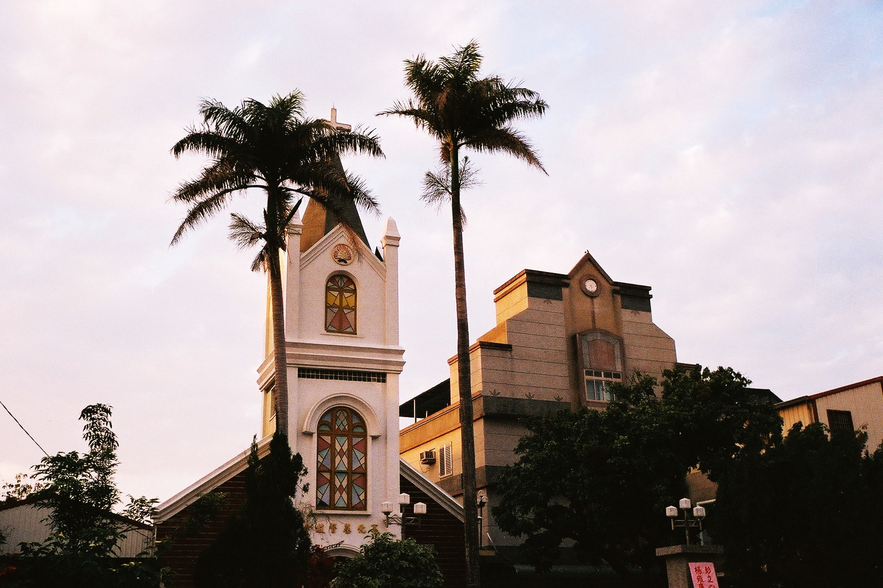 a large tall white church with palm trees in front of it