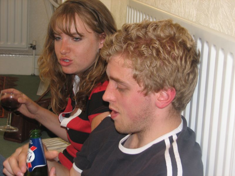 two people sitting at a table holding a glass of wine and a bottle of beer