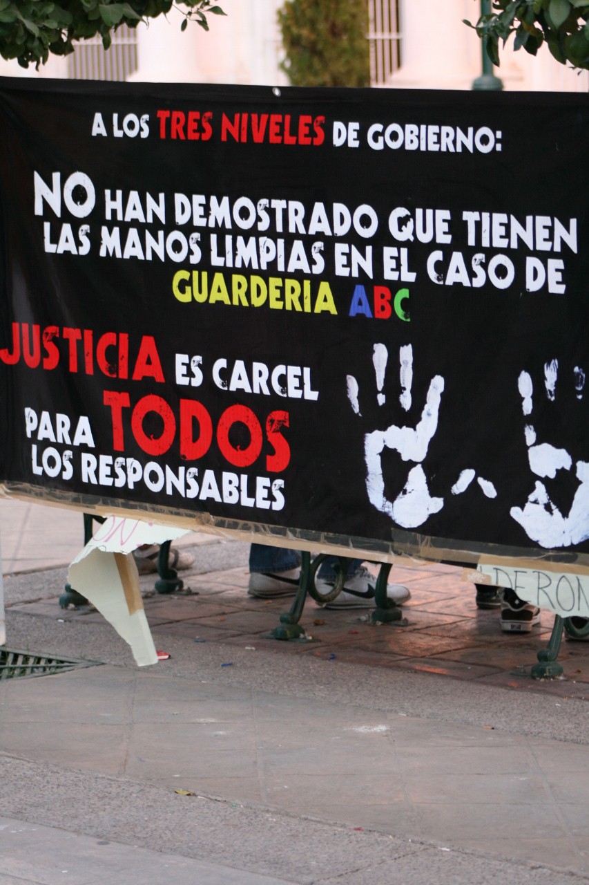 protest sign with black background and white hand prints