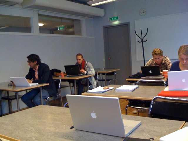 people sitting at desk using laptops in a classroom