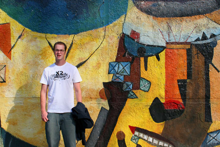 a man standing next to a wall with graffiti on it