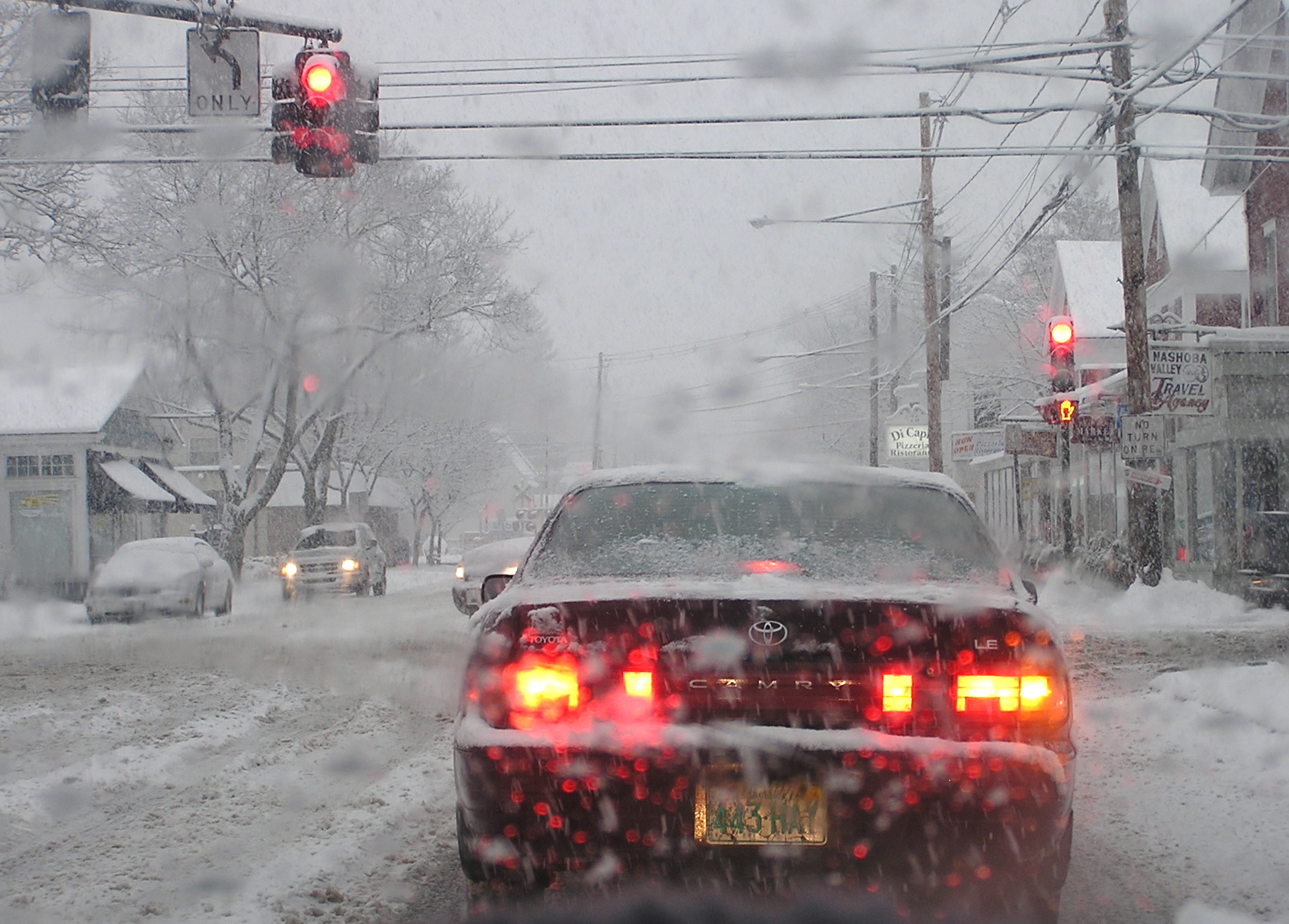 a car driving down a snow covered street with traffic lights