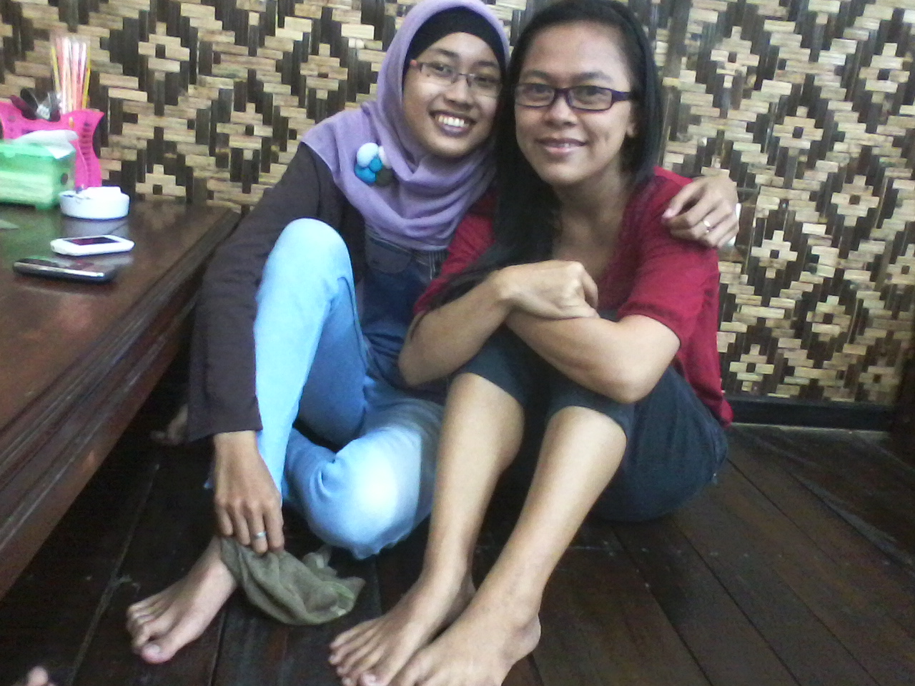 two women pose for the camera while on a wood floor