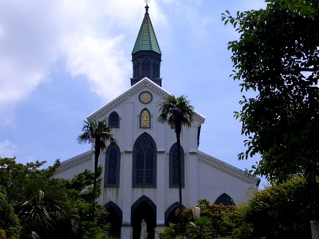 the view of a church with many trees and sky in the background