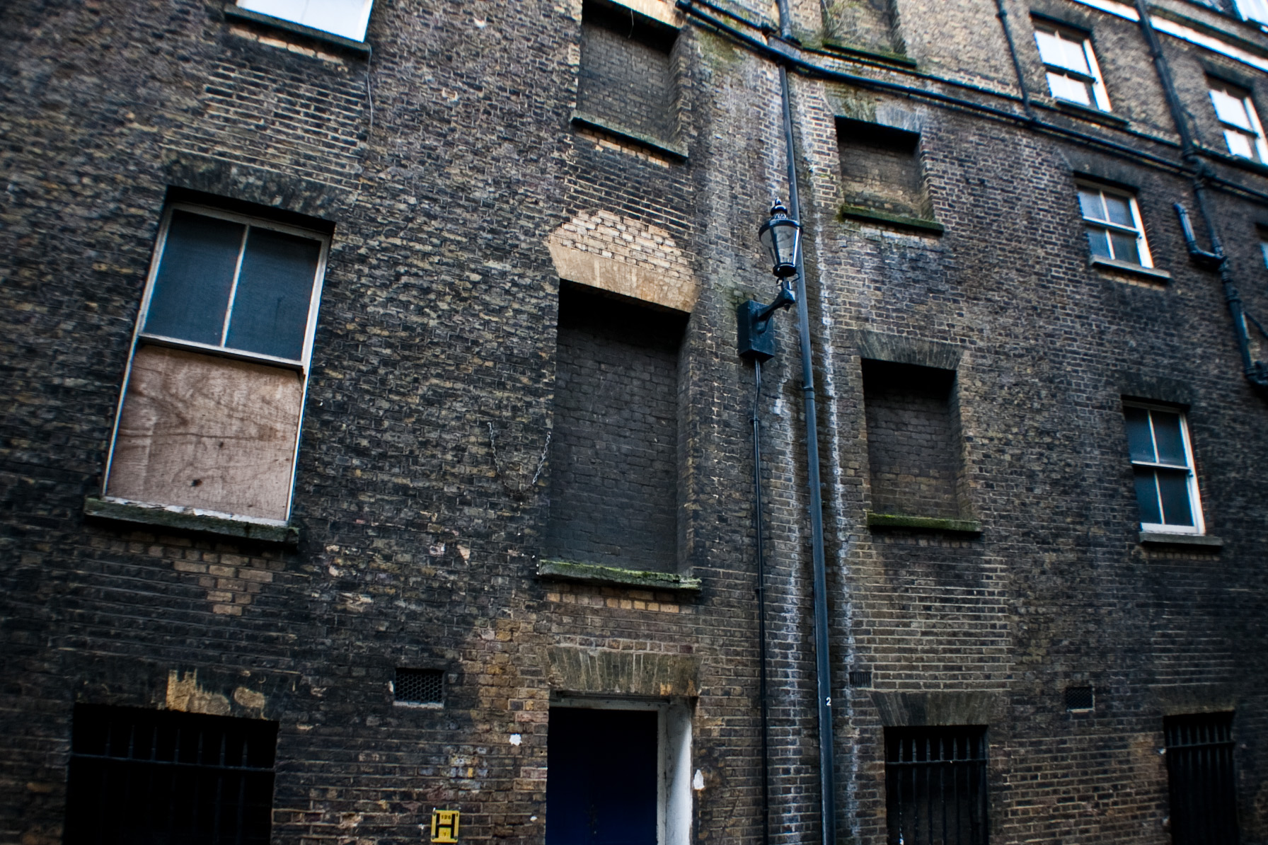 a dark brick building with windows, and a street sign