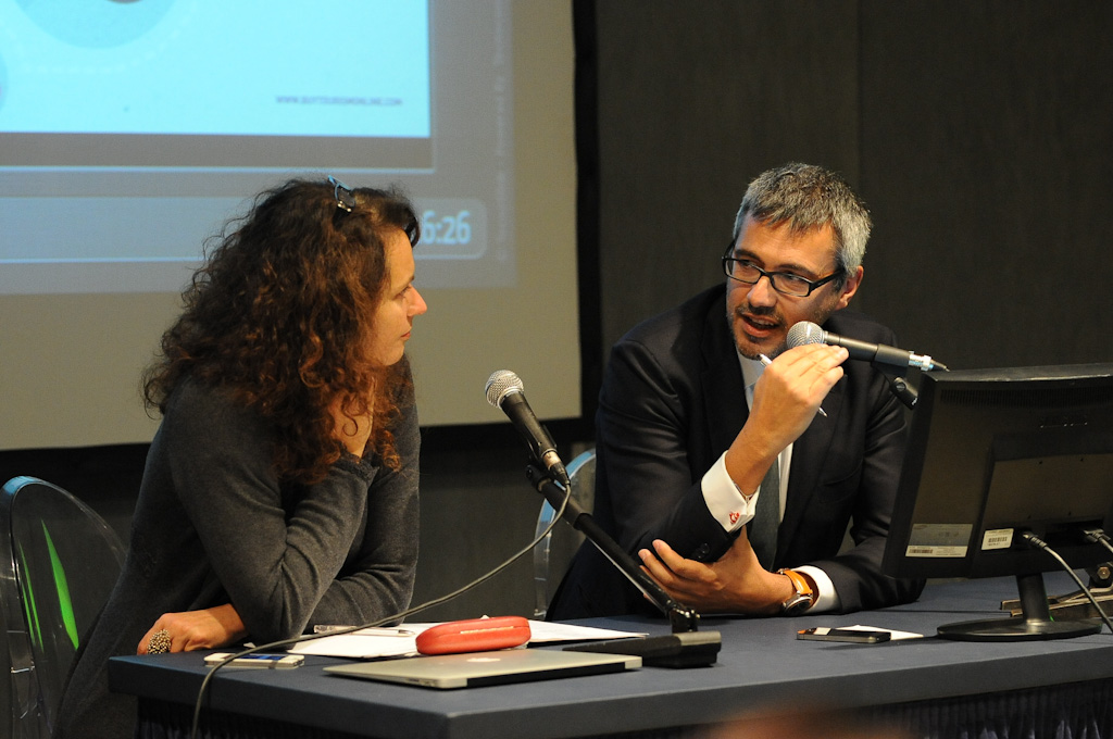 a man and woman sitting at a table with microphones