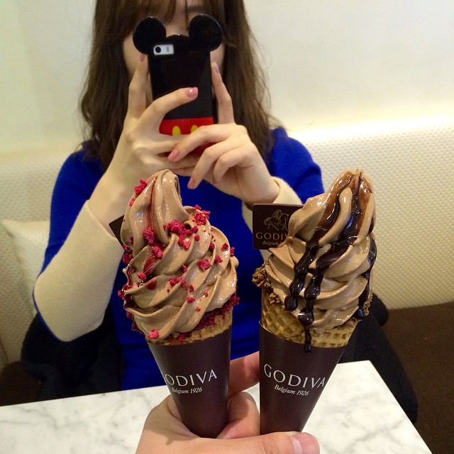 woman taking selfie of desserts in an ice cream shop