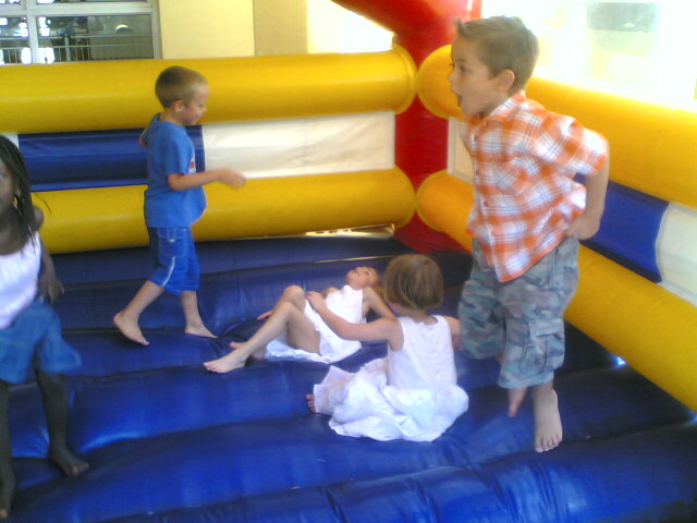 two children are sitting on the ground in an inflatable bounce house