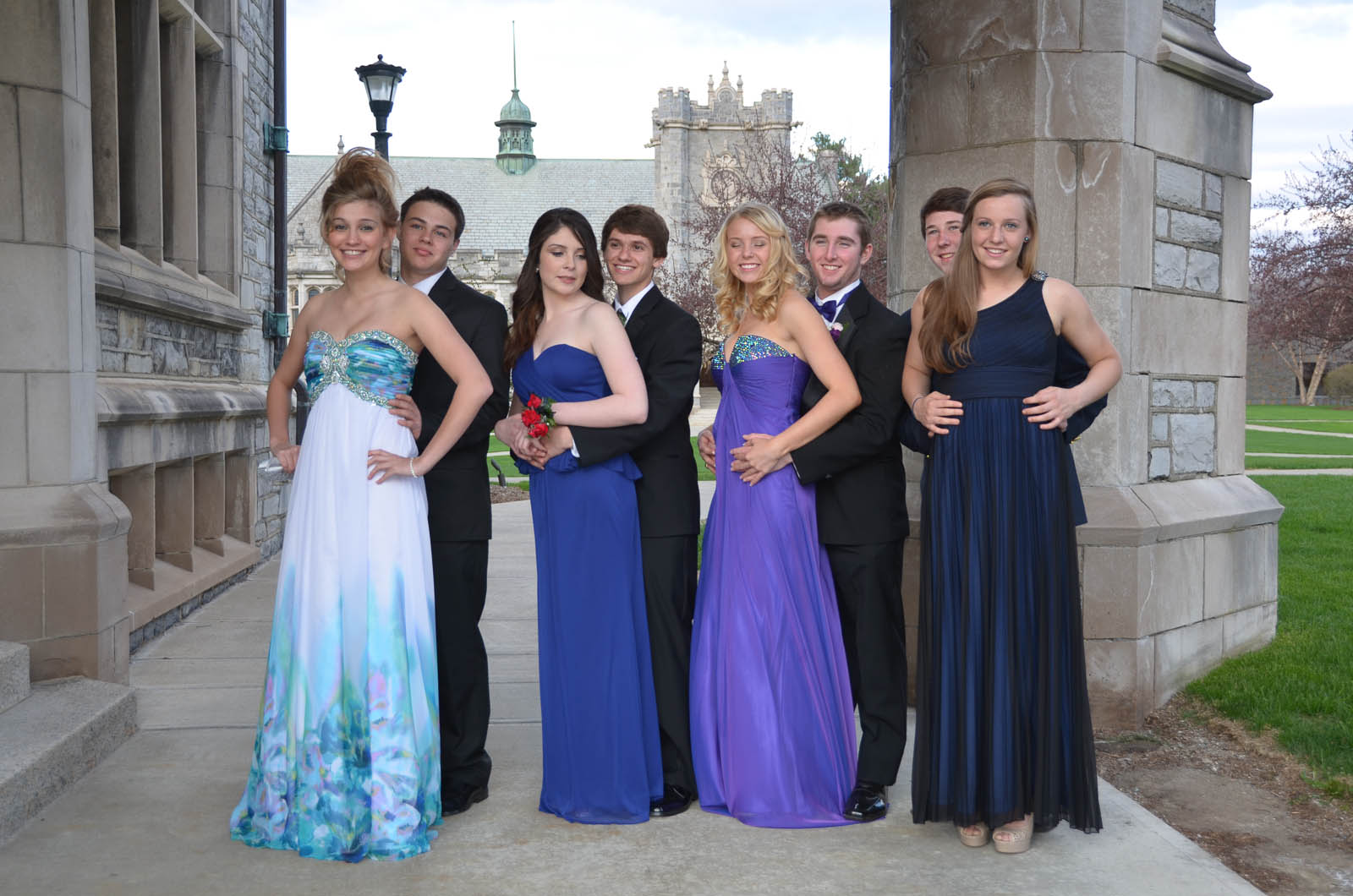 several women and two men standing in formal wear outside