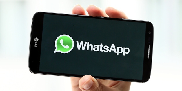 a hand holding up a smart phone displaying whatsapp