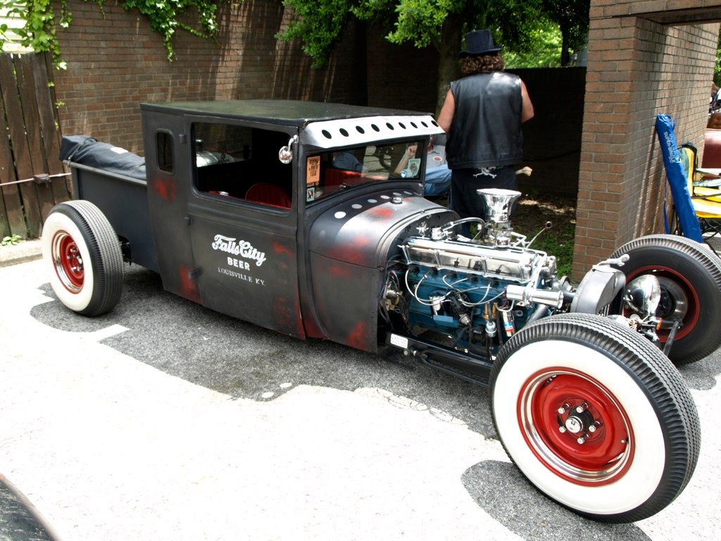 an old fashioned  rod car in a parking lot