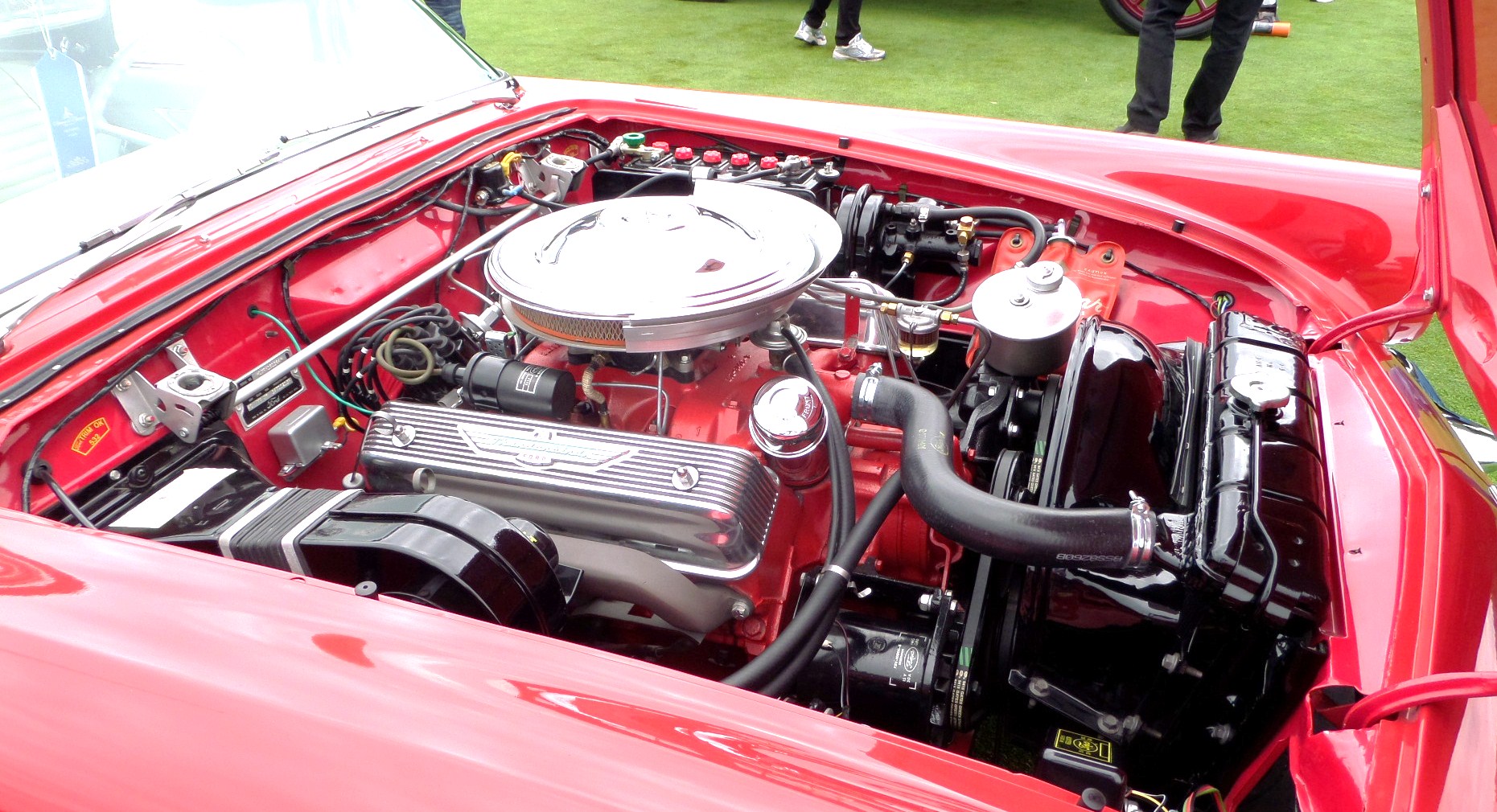 an engine bay in a red vehicle at a car show