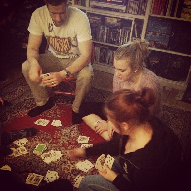 a group of people sitting around playing with cards