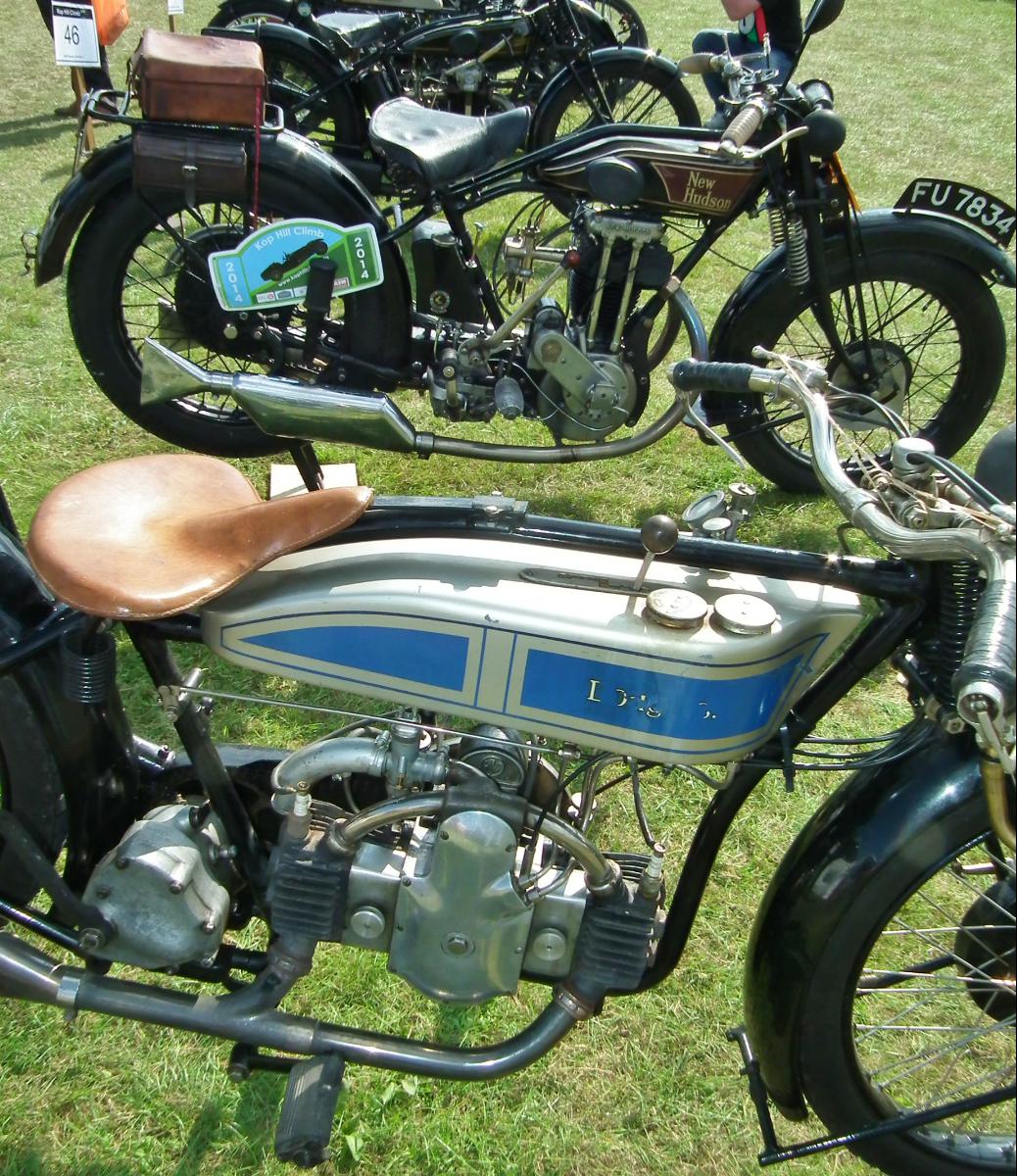 an antique motorcycle with several wooden seats parked in the grass