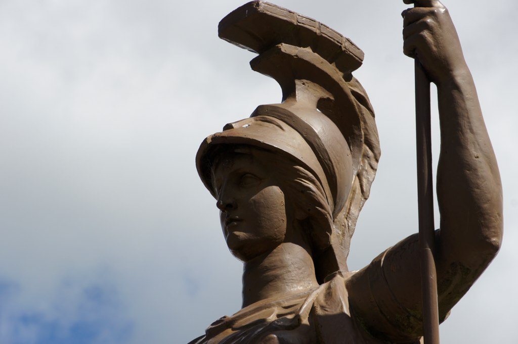 a statue holds a long pole next to its head