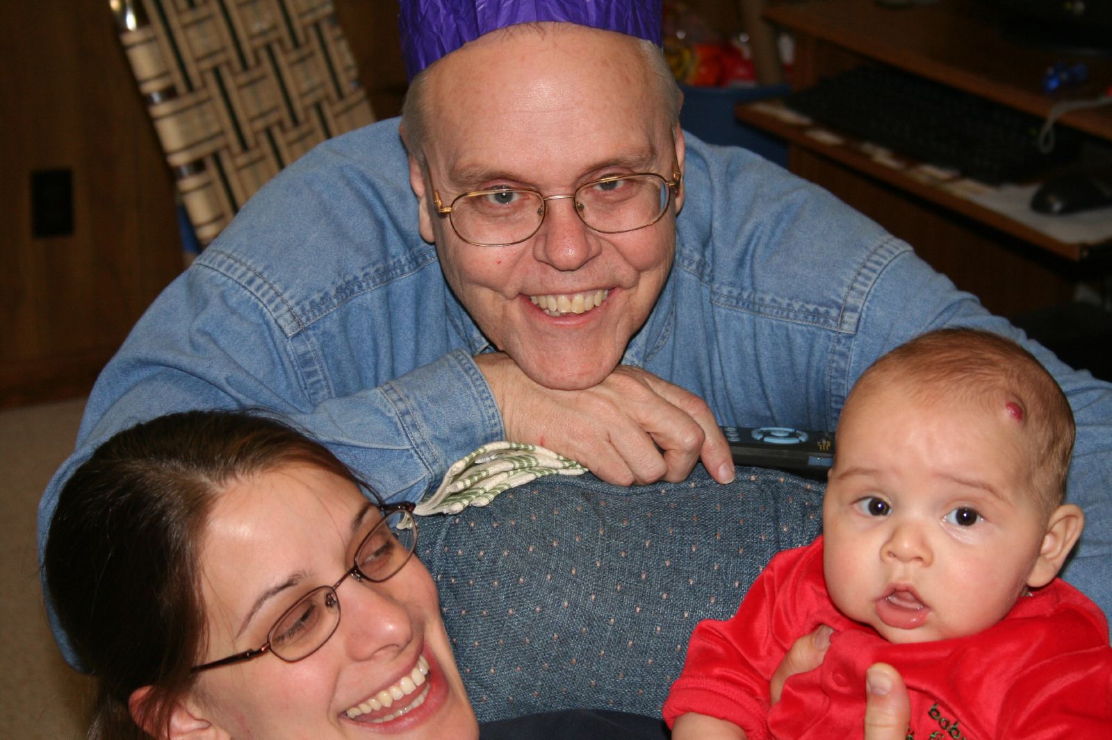 a smiling man holding a baby wearing glasses