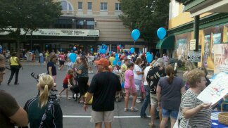 a large group of people on a city street with balloons and banners