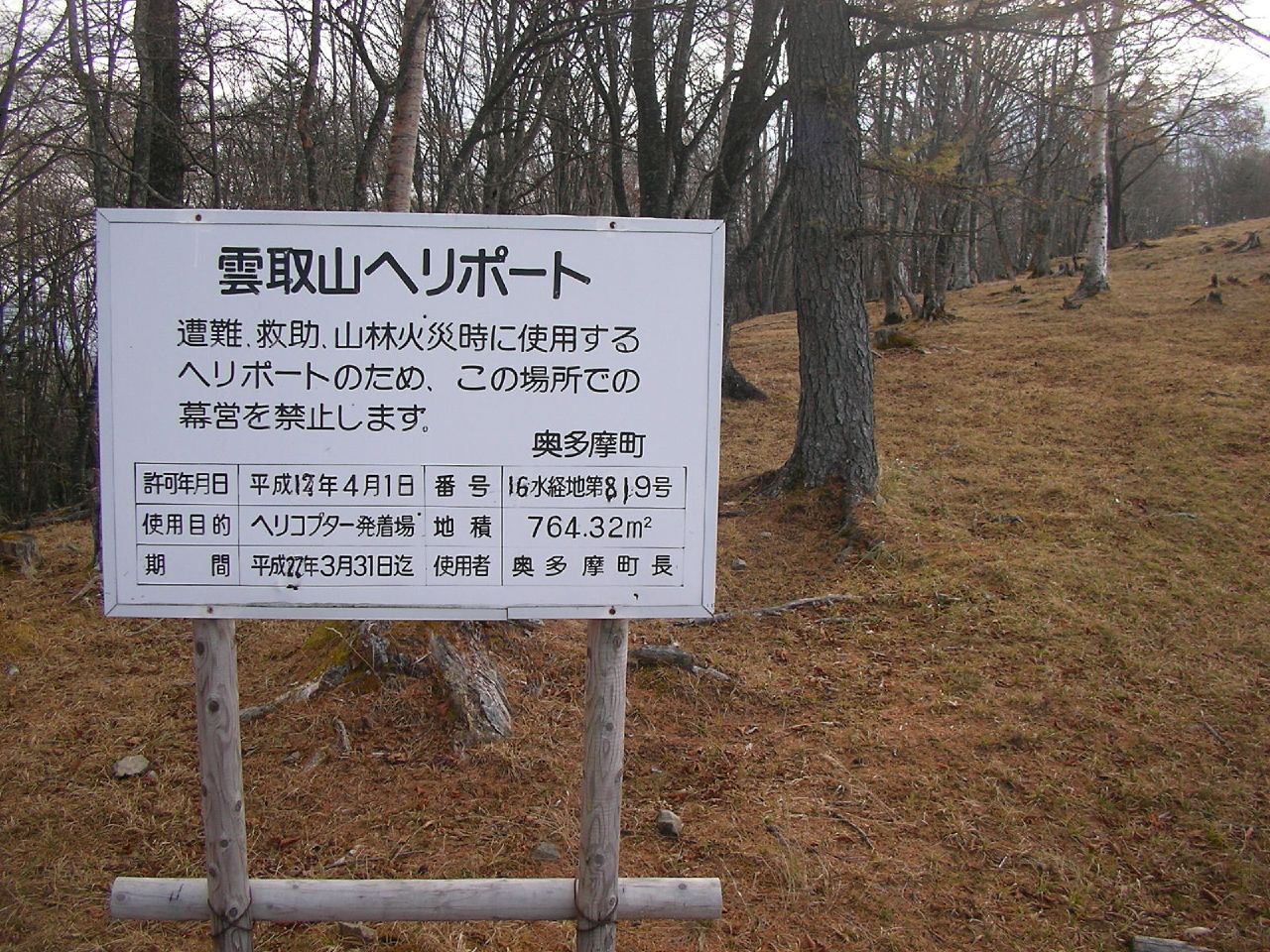 a sign posted in front of a forest area