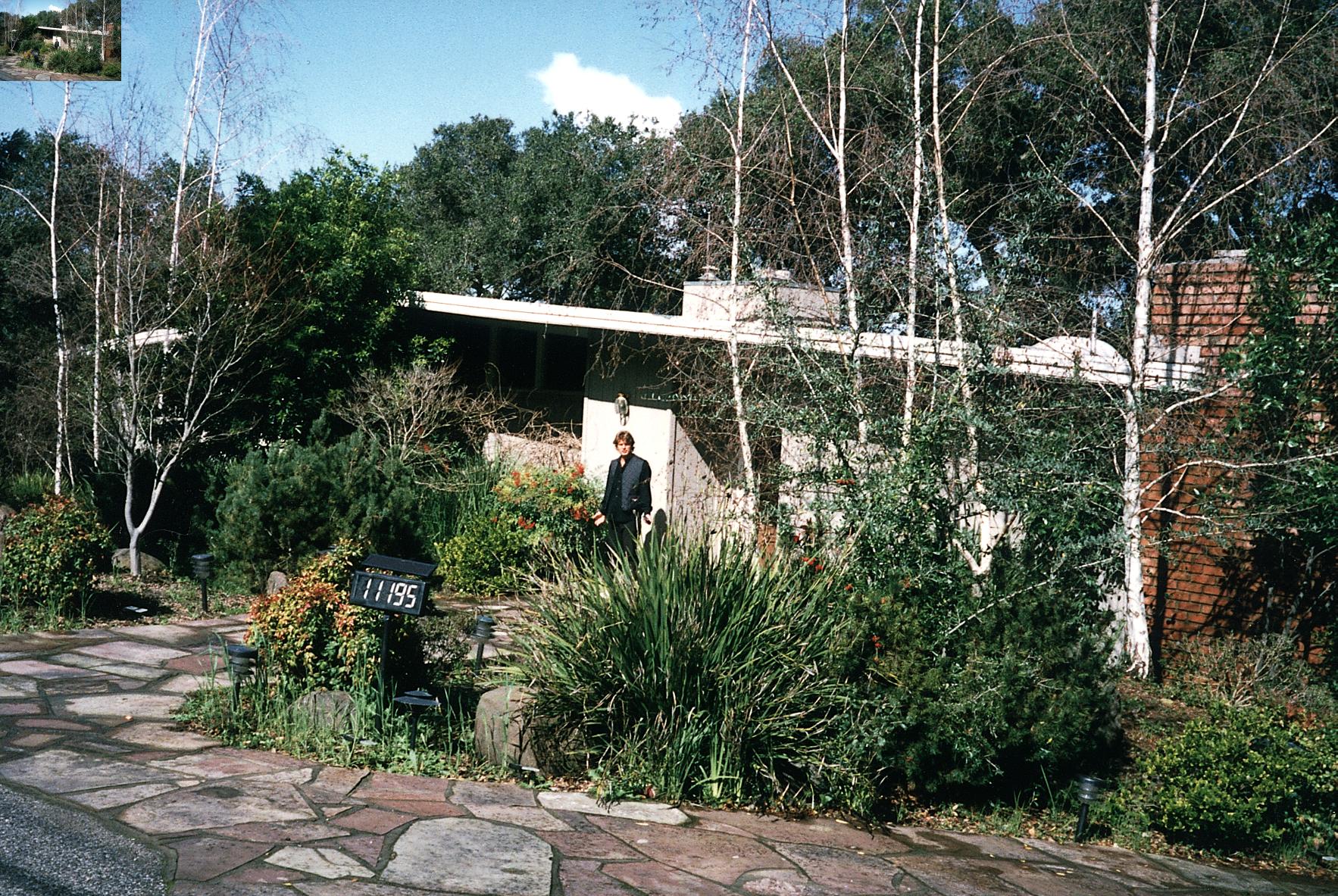 a man standing in front of an overgrown building