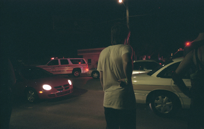 a man stands in front of several cars at night