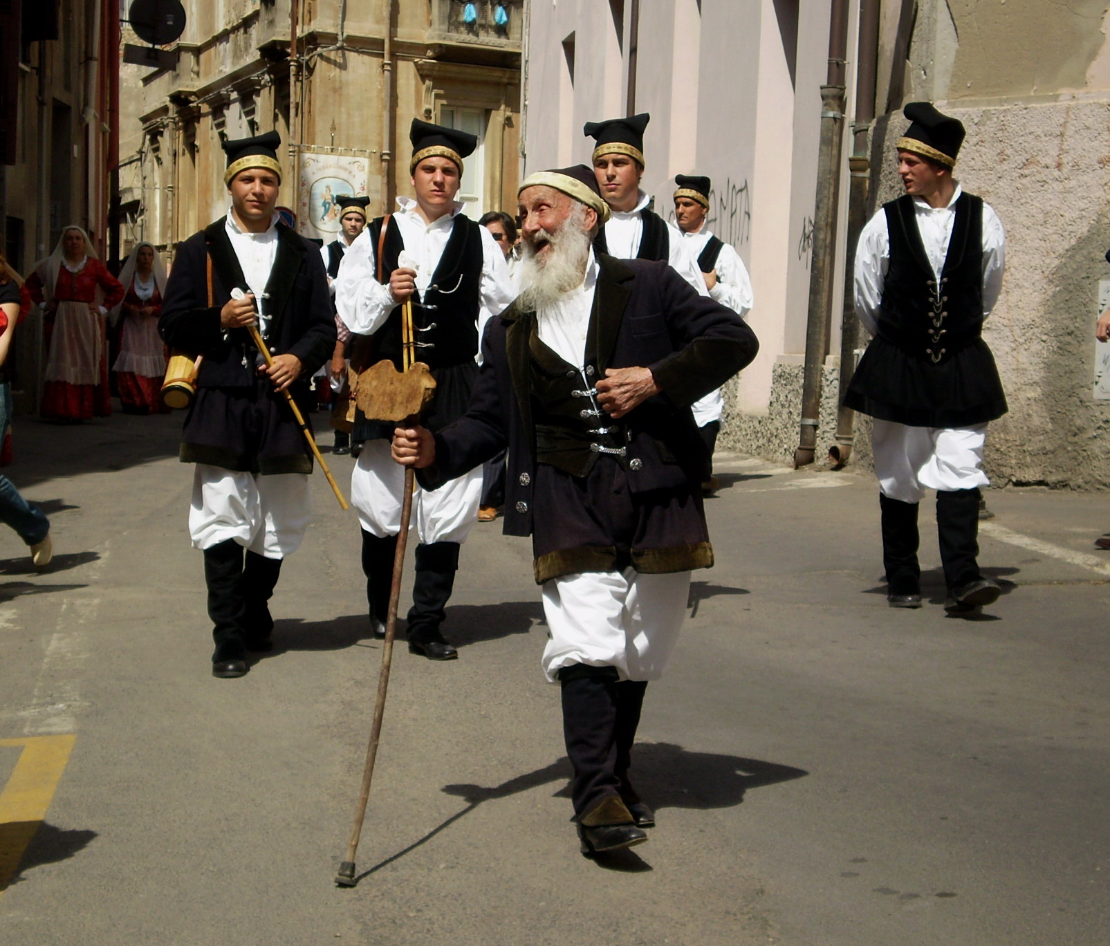 a group of people dressed in traditional clothing walk on a city street