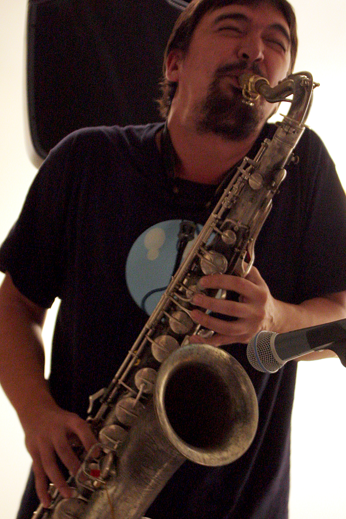 a man with a saxophone is laughing and holding a microphone