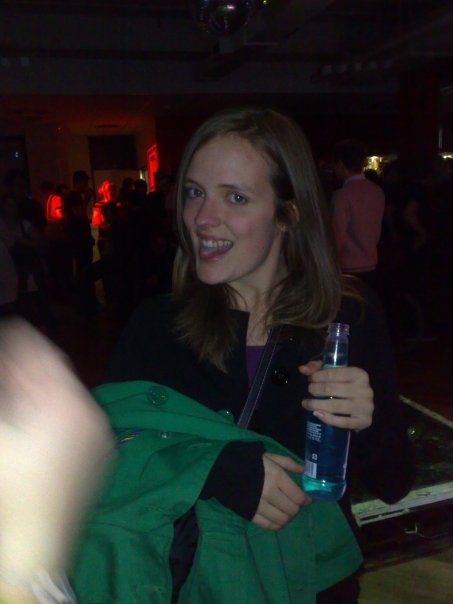a woman wearing black jacket holding up a blue bottle