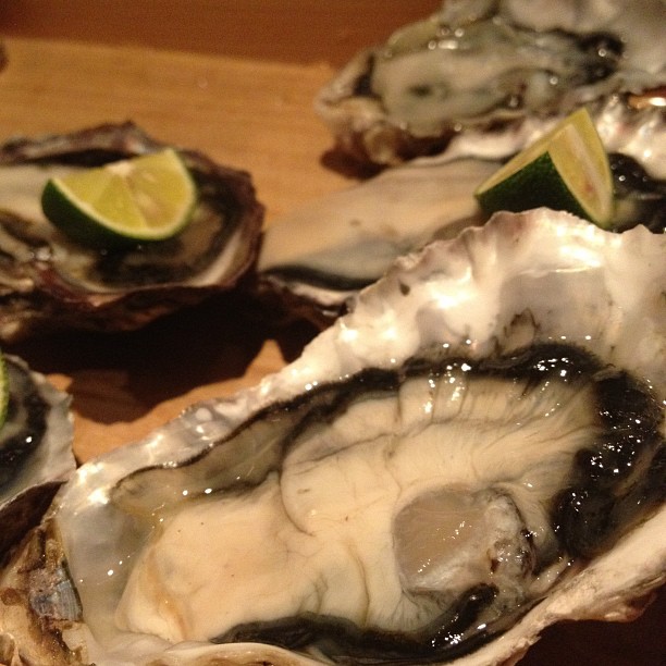 oysters sit on the chopping board with lime wedges
