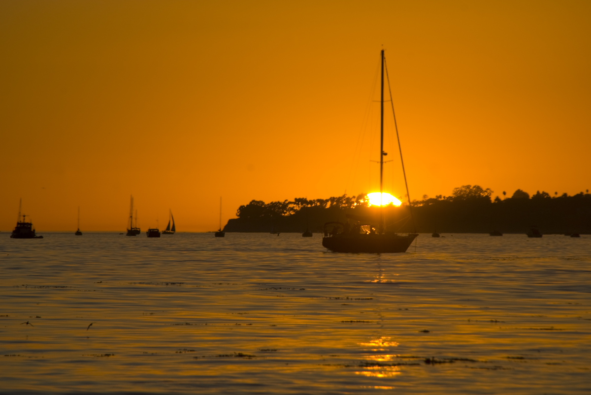 the sun setting over several boats in the water