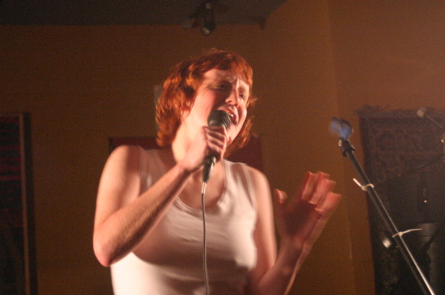 a woman with red hair holding a microphone in her hands