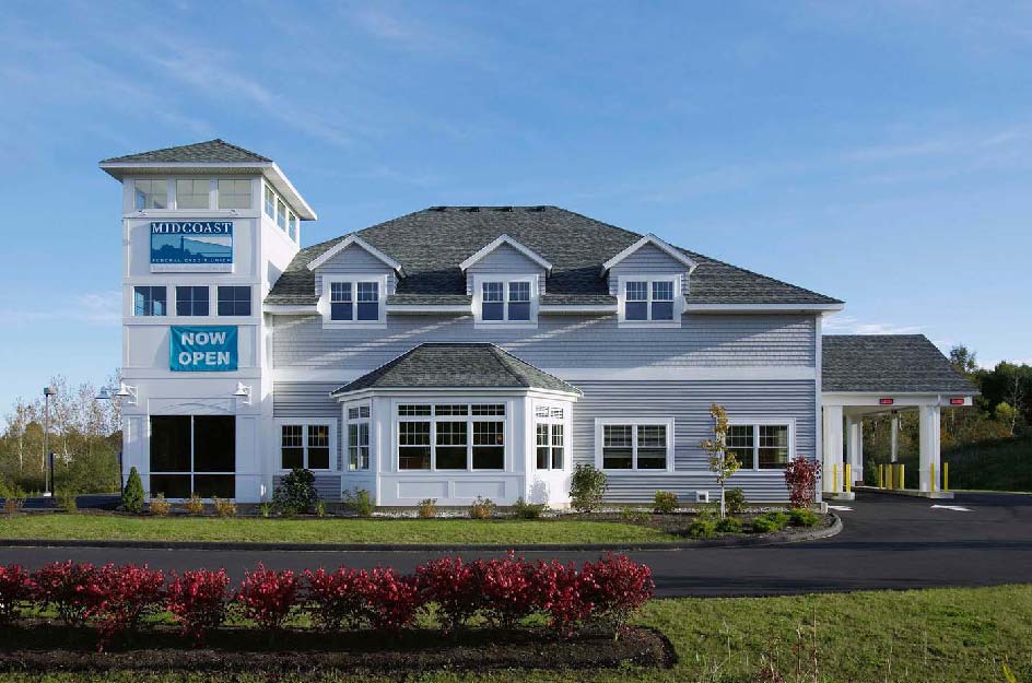 a large white building with flowers and landscaping outside