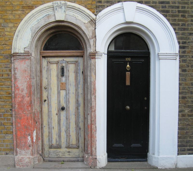 two doors side by side in front of a brick wall