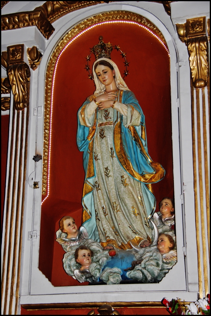 the painted image of mother mary stands high up