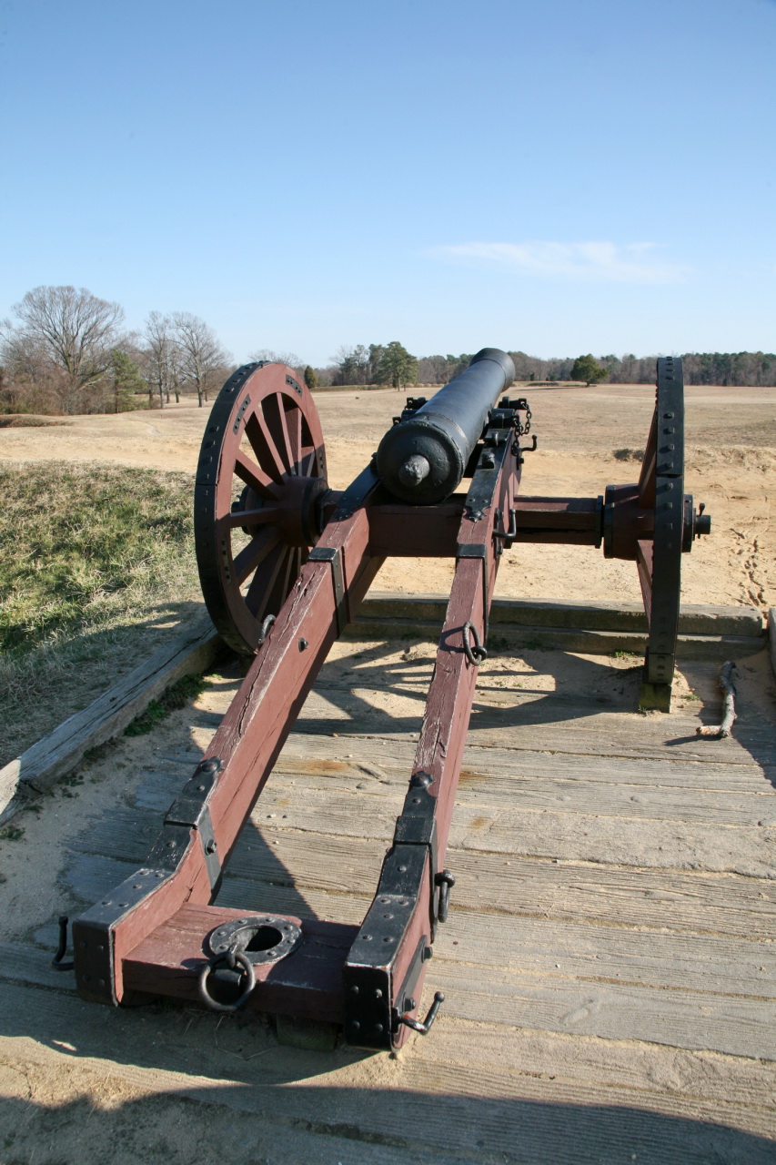 a wooden gun laying on the ground with two wheels and one of its wheels removed