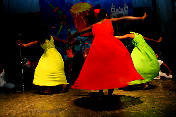 a group of people in brightly colored dresses doing a dance routine