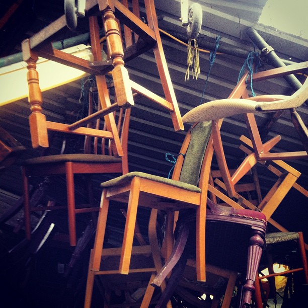 some old chairs with arms and legs are stacked up in a room